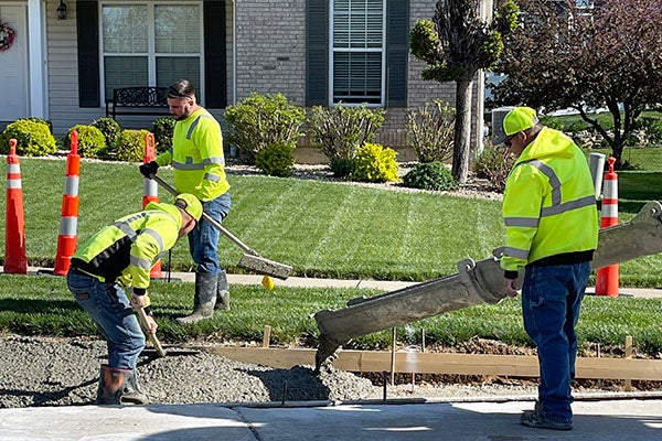 people laying down concrete in front of a house