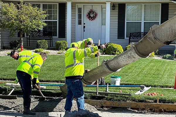 people laying down concrete in front of a house