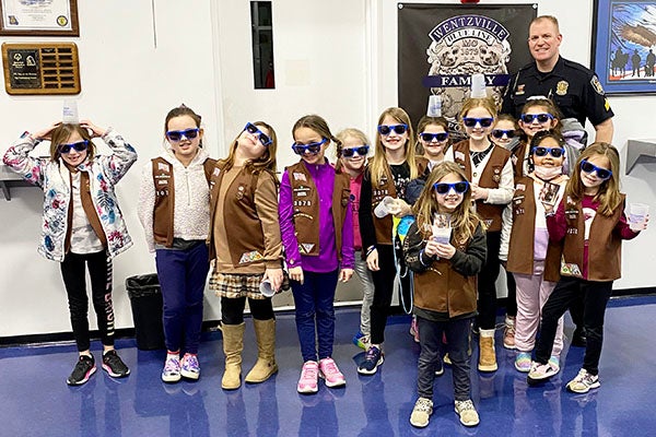 Kids posing with sunglasses next to a police officer