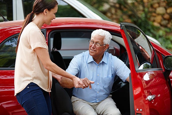 Woman assisting elderly man get out of a car