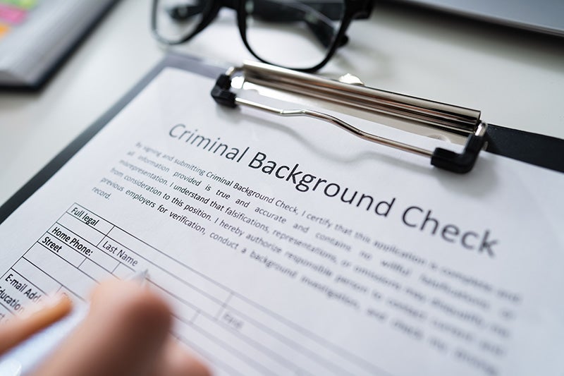 A close up of a person completing a criminal history background form.