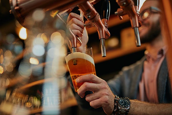 man pouring beer into a glass cup