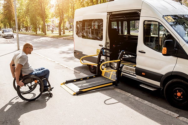 A man in a wheelchair moves to the lift of a specialized vehicle for people with disabilities.