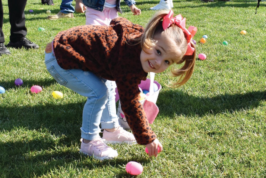 Young girl picking up Easter egg