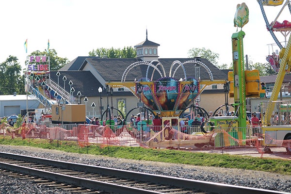 alt= Carnival rides are on the other side of the railroad tracks.