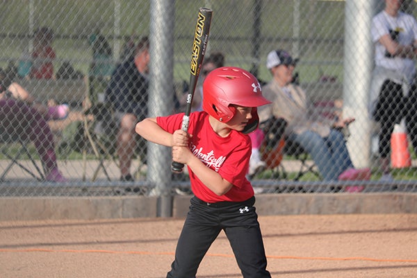 alt= A baseball player in a red Wentzville uniform, black pants and a red batter's helmet stands in position, ready to bat.