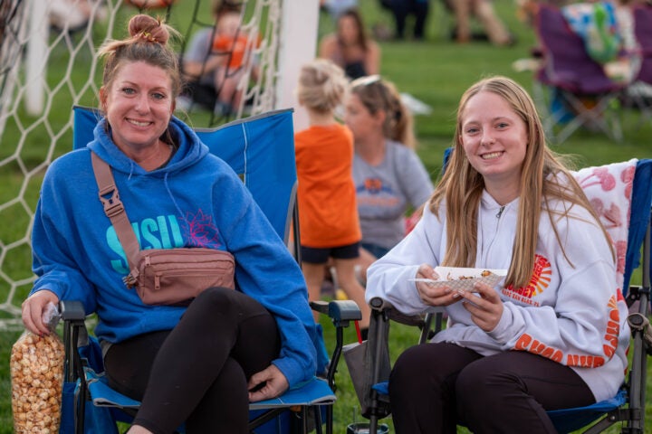 mother and daughter sitting in lawn chairs on a soccer field