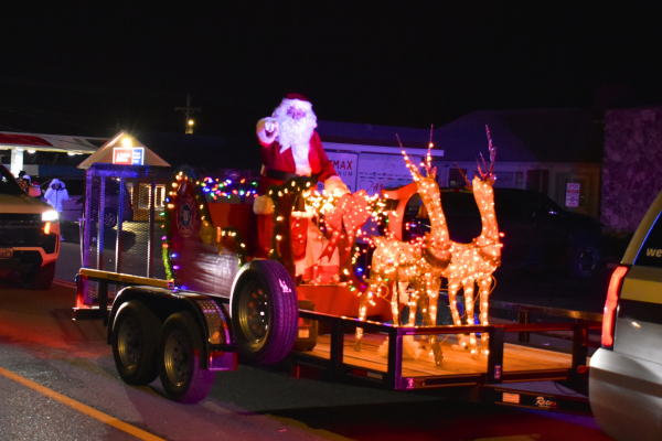 Santa on trailer standing behind reindeer made of lights