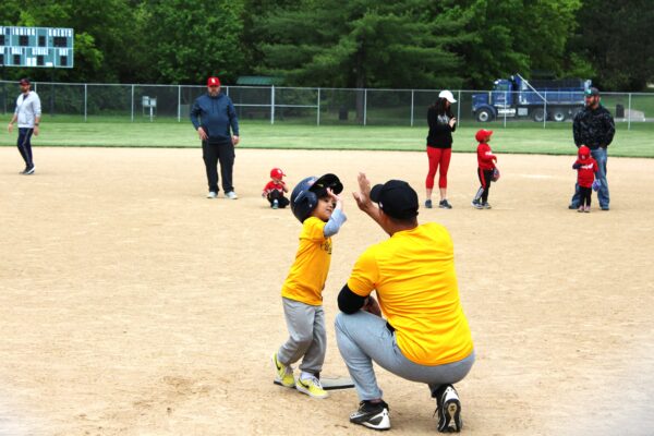 coach and young baseball player high-fiving