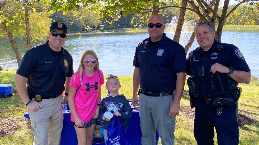 Police officers and kids standing in front of a lake.