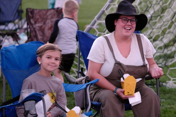 three people sitting in lawn chairs eating snacks on a soccer field
