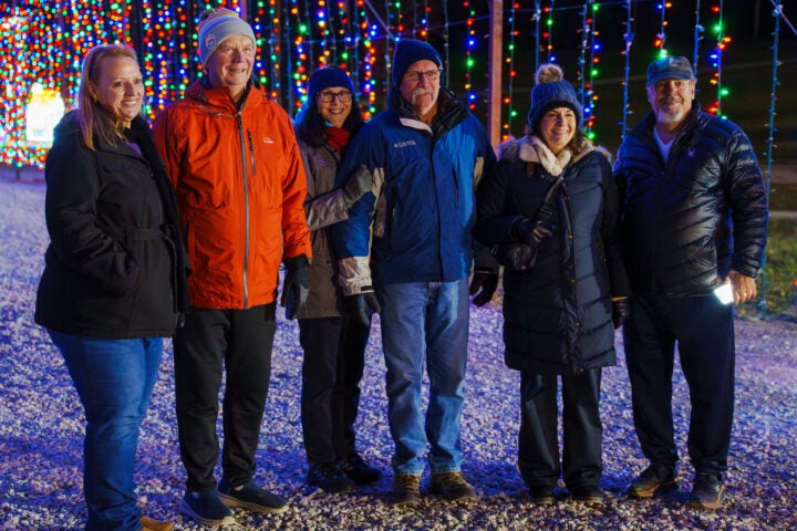 A group of adults standing inside a colorful light tunnel next to one another