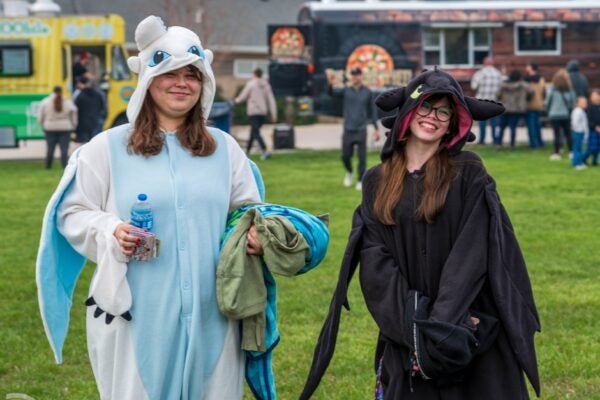 Two teens in dragon costumes in front of food trucks
