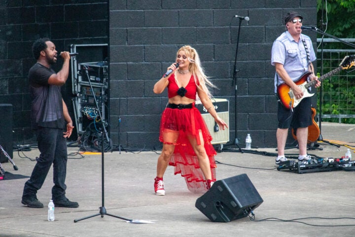 three bands members performing on an outdoor stage