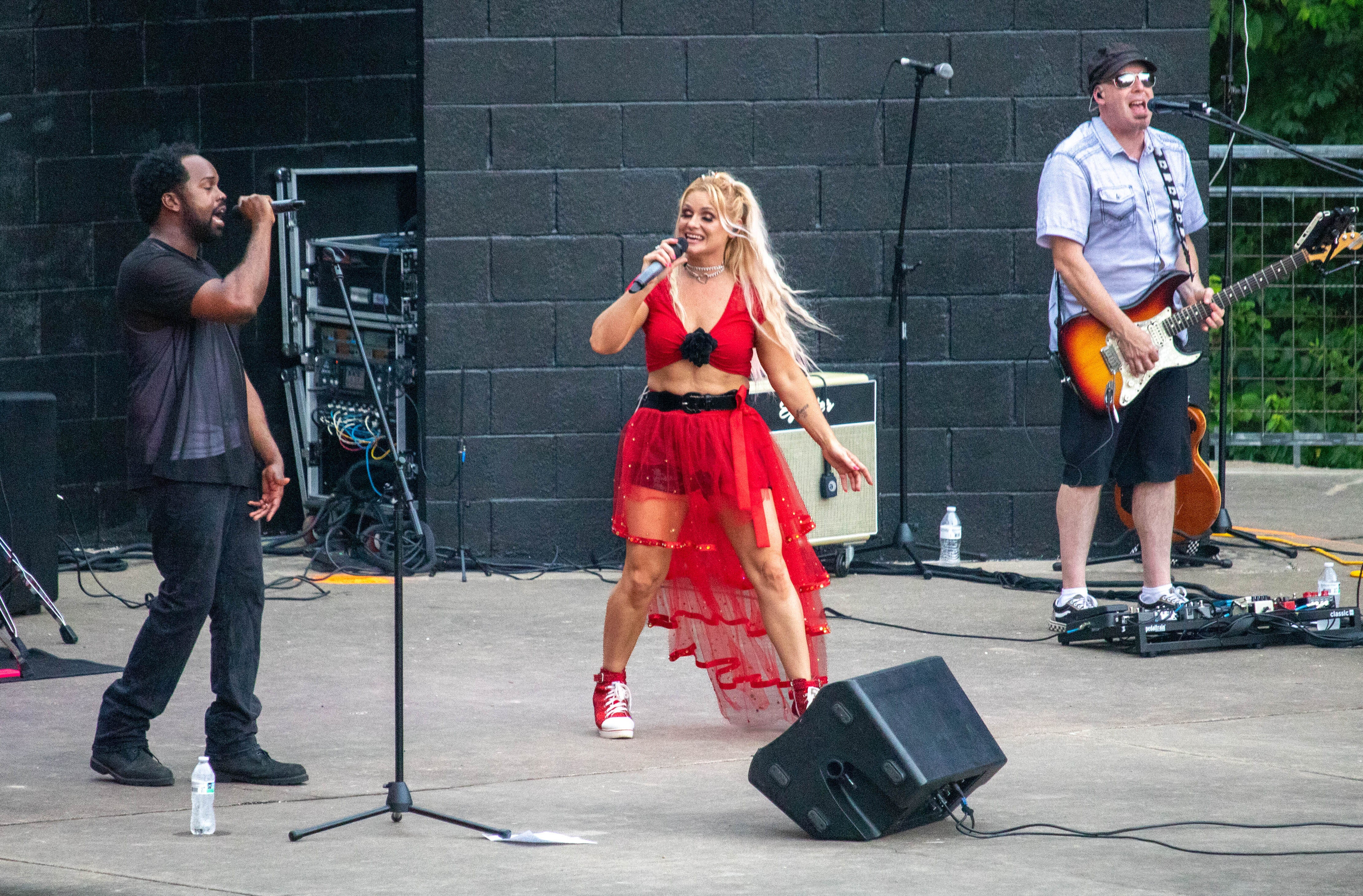three bands members performing on an outdoor stage